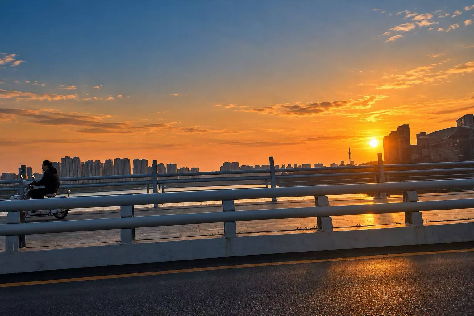 桥上的骑行者与落日下的城市