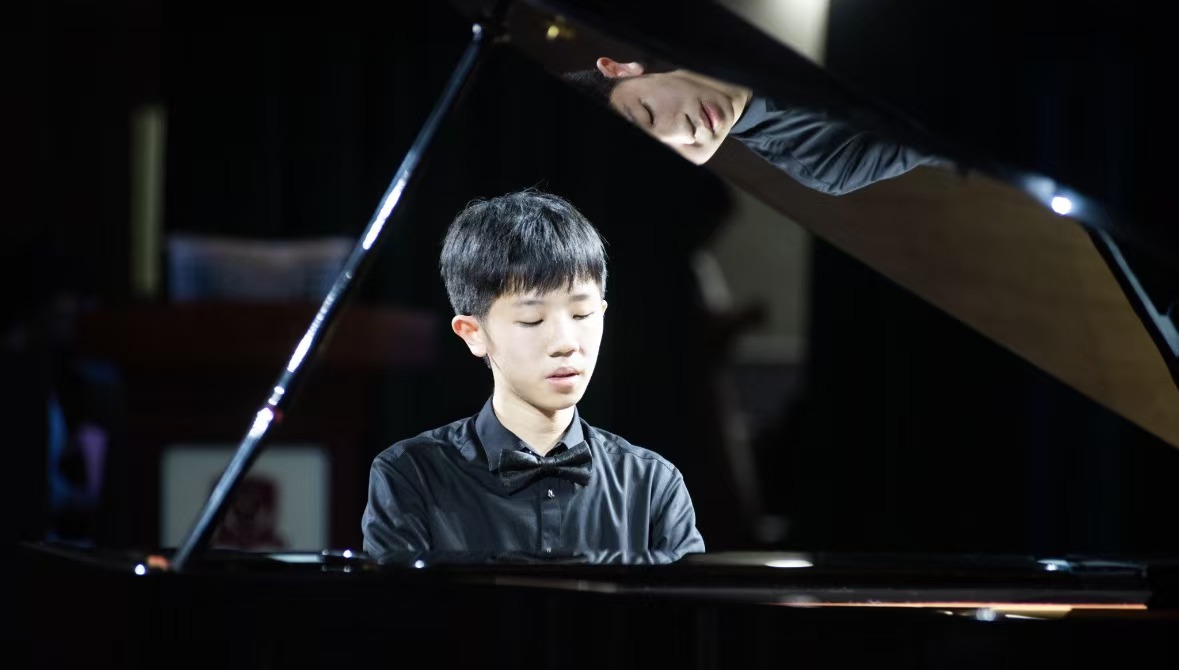 李晨涛在三角钢琴前演奏,琴盖映出倒影